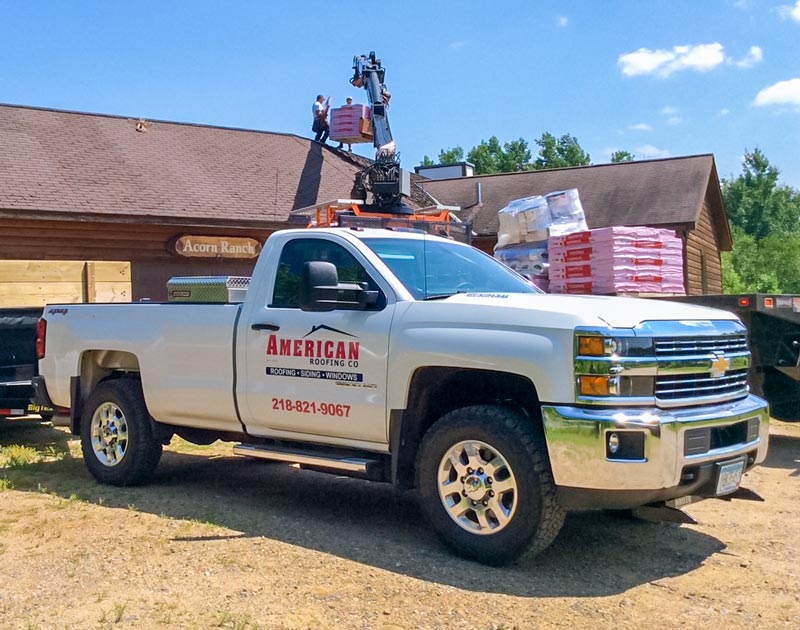 Company vehicle with workers on roofing job site